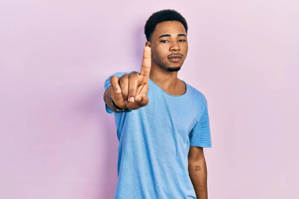 若いアフリカ系アメリカ人の男性は 指を上げて怒りの表情で指差すカジュアルなブルーのTシャツを着て ジェスチャーを示さない — ストック写真
