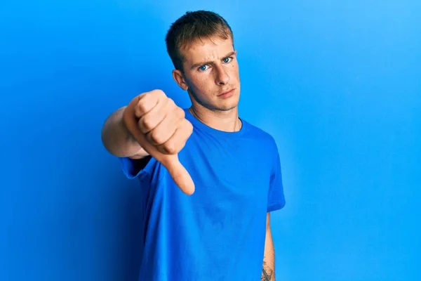 年轻的高加索人穿着休闲的蓝色T恤 看起来很不高兴 很生气 带着拒绝和负面的手势 不好的表达方式 — 图库照片