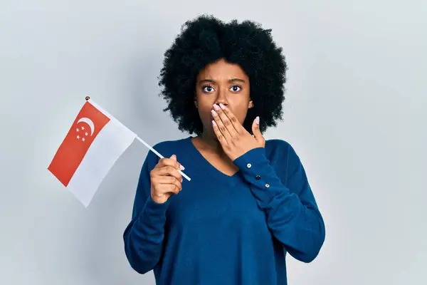 Young African American Woman Holding Singapore Flag Covering Mouth Hand — Stock Photo, Image