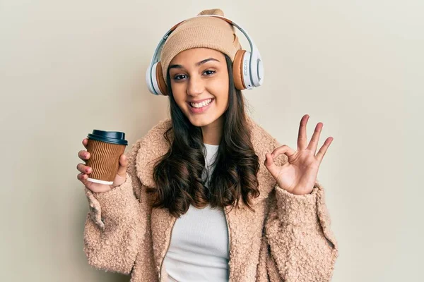 Mulher Hispânica Jovem Usando Fones Ouvido Beber Café Fazendo Sinal — Fotografia de Stock