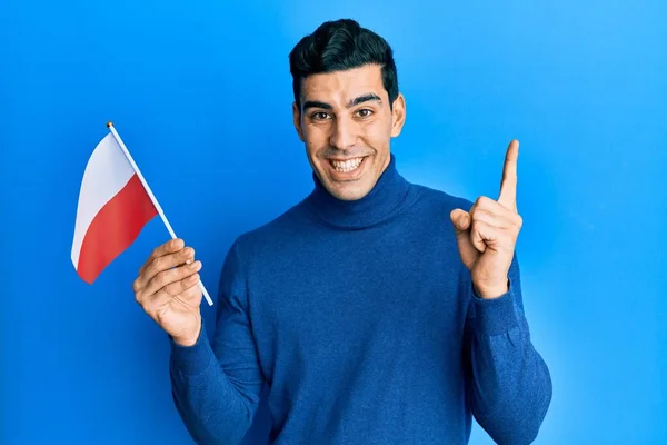 Hombre Hispano Guapo Sosteniendo Bandera Polonia Sonriendo Feliz Señalando Con —  Fotos de Stock