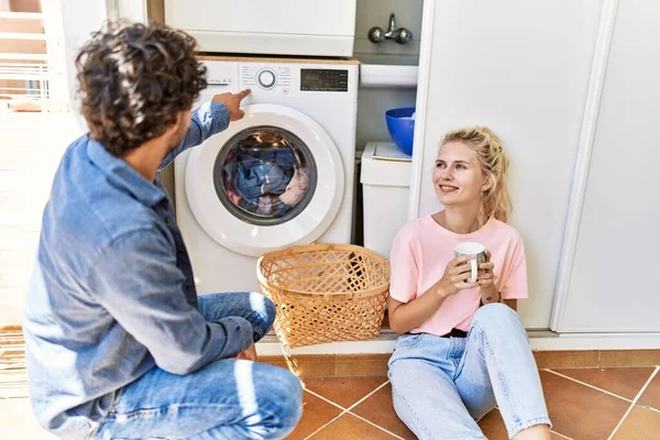 Young Couple Smiling Happy Drinking Coffee While Doing Laundry Home — Stock Photo, Image