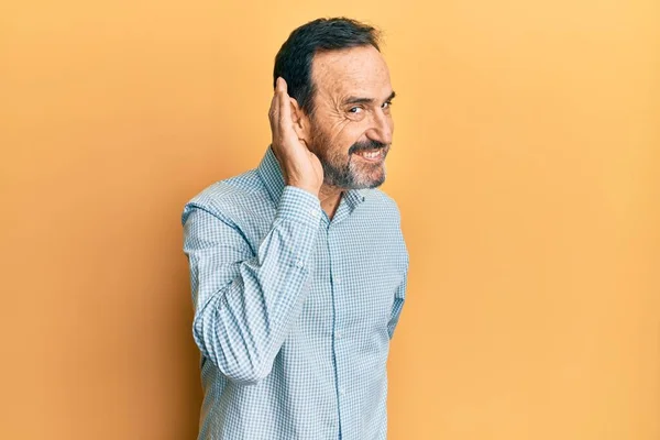 中世のヒスパニック系の男性は 耳を傾け 噂やゴシップに耳を傾け手で笑みを浮かべてカジュアルな服を着ていた 聴覚障害の概念 — ストック写真