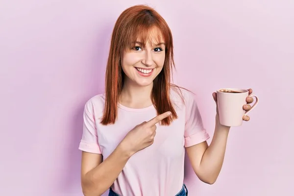 Rödhårig Ung Kvinna Dricker Kopp Kaffe Ler Glad Pekar Med — Stockfoto