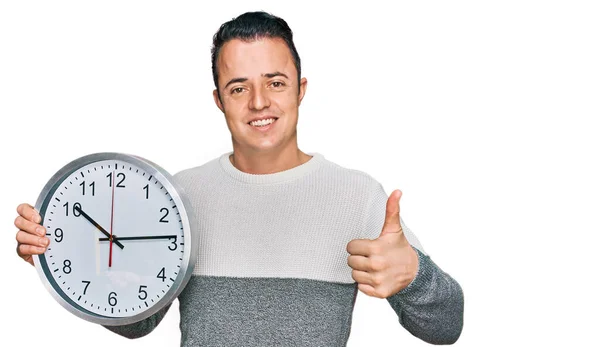 Bonito Jovem Segurando Grande Relógio Sorrindo Feliz Positivo Polegar Para — Fotografia de Stock