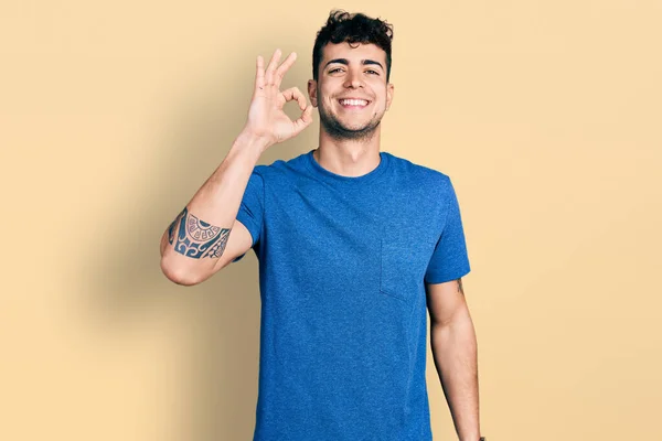 Joven Hombre Hispano Vistiendo Camiseta Casual Sonriendo Positiva Haciendo Señal —  Fotos de Stock