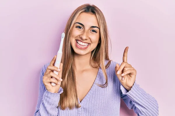 Beautiful Hispanic Woman Holding Electric Toothbrush Smiling Happy Pointing Hand — Stock Photo, Image