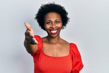 Genç Afrikalı Amerikalı kadın günlük kıyafetler giyip gülümseyerek dostça tokalaşıyor ve hoş geldin diyor. başarılı iş. 