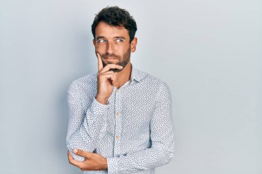 Sakallı, şık tişörtlü, yakışıklı, ciddi yüzlü, eli çenesinde soru soran, kafa karıştırıcı fikirli, düşünceli bir adam. 