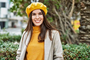 Genç İspanyol kız gülümseyerek şehirde mutlu mesut dikiliyor..