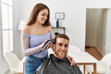 Genç bir kadın erkek arkadaşının saçını kesiyor..