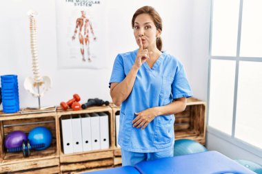 Orta yaşlı İspanyol fizyoterapist kadın ağrı kesici kliniğinde çalışıyor ve sessiz olmak istiyor. sessizlik ve gizli konsept. 