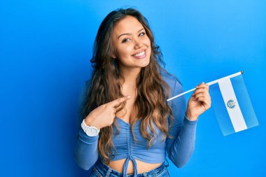 El Salvador bayrağını tutan genç İspanyol kız mutlu bir şekilde el ve parmağıyla işaret ediyor. 