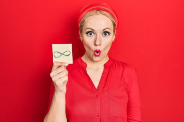 Sarışın genç kadın elinde sonsuz bir sembol tutuyor. Korkmuş ve şaşırmış bir şekilde ağzı açık bir şekilde şaşırmış, inançsız bir yüz. 