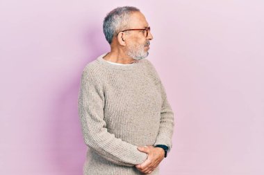 Sakallı, sıradan süveter ve gözlüklü, kolları çapraz ve kendinden emin yakışıklı bir adam. 