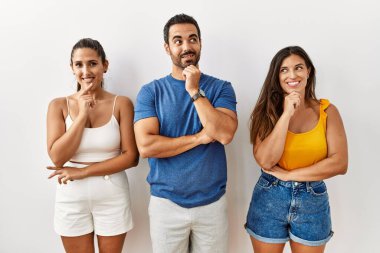 Tecrit edilmiş bir arka planda, elleri çenesinde soru soran, düşünceli bir grup İspanyol genç insan. Gülümseyen ve düşünceli bir yüz. şüphe kavramı. 