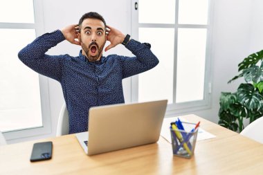 Ofiste sakallı, sakallı, deli ve elleri başında korkmuş, ağzı açık bir şekilde şok geçirmekten korkan genç bir İspanyol. 