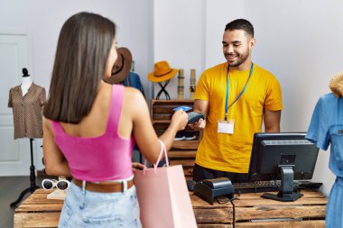 Genç Latin müşteri mağazada kredi kartıyla dükkan sahibine ödeme yapıyor..