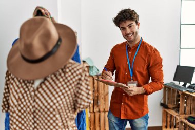 Genç İspanyol esnaf gülümsüyor. Giyim mağazasında çalışan panoya mutlu yazılar yazıyor..