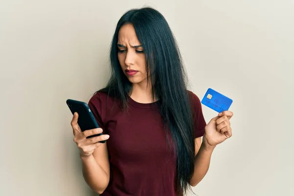 Ung Latinamerikansk Flicka Håller Smartphone Och Kreditkort Skeptisk Och Nervös — Stockfoto