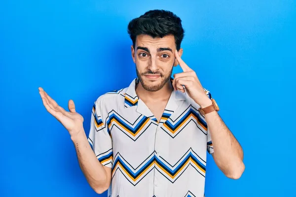 Gündelik giysiler giyen genç İspanyol adam avuç içi açık fotokopi alanı gösterip alnını işaret etmekten rahatsız oluyor. Bunu bir düşün.. 