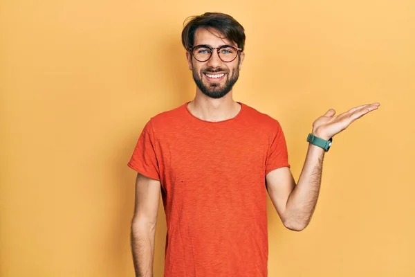 Nuori Latino Mies Yllään Rento Vaatteita Lasit Hymyilevä Iloinen Esittelee — kuvapankkivalokuva