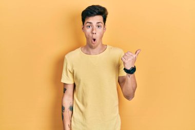 Gündelik sarı tişört giyen İspanyol genç adam elini yana doğru göstererek şaşırdı, ağzı açık hayret içinde kaldı.. 