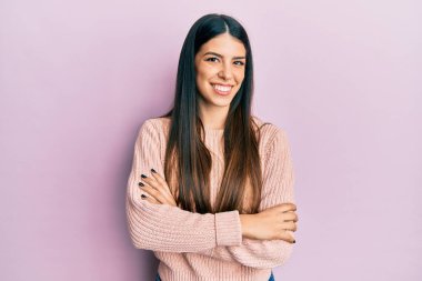 Gündelik kıyafetler giyen, kollarını kavuşturup kameraya gülümseyen genç İspanyol kadın. pozitif kişi. 