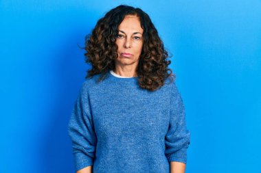 Orta yaşlı İspanyol kadın, günlük giysiler giyiyor, depresyonda ve endişe içinde, kızgın ve korkmuş bir şekilde ağlıyor. hüzünlü ifade. 