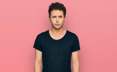 Gündelik siyah tişört giyen, kuşkucu ve gergin genç yakışıklı bir adam sorun yüzünden surat asıyor. negatif kişi. 