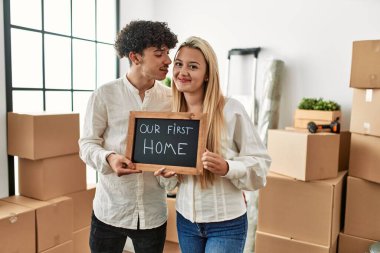 Genç ve güzel bir çift gülümsüyor. İlk ev mesajımızla birlikte ellerinde tahta tutuyorlar..