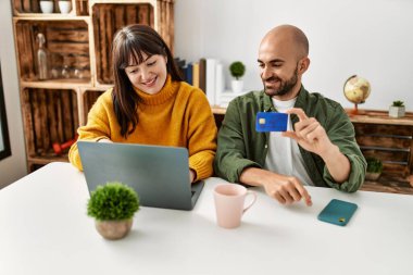 Genç İspanyol çift dizüstü bilgisayar ve kredi kartı kullanarak mutlu bir şekilde gülümsüyor..