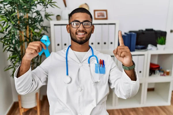 Young Indian Doctor Holding Blue Ribbon Surprised Idea Question Pointing — Stock Photo, Image