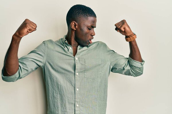 Young african american man wearing casual clothes showing arms muscles smiling proud. fitness concept.