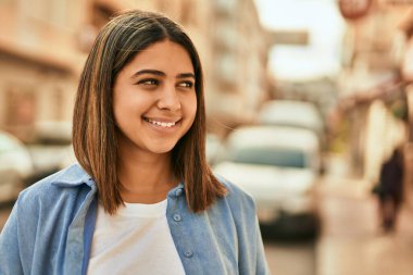 Genç Latin kız gülümseyerek şehirde mutlu mesut dikiliyor..