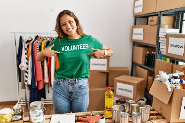 Bağışta gönüllü tişört giyen güzel İspanyol kadın yüzünde bir gülümsemeyle ayakta duruyor, kendini gururlu ve mutlu bir şekilde gösteriyor.. 