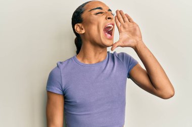 Makyaj yapan, uzun saçlı, günlük tişörtlü, bağıran ve el üstünde ağızla bağıran İspanyol bir adam. iletişim konsepti. 