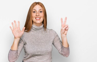 Genç İrlandalı kadın gündelik giysiler giyer ve yedi numaralı parmaklarıyla işaret ederken kendinden emin ve mutlu bir şekilde gülümserdi.. 