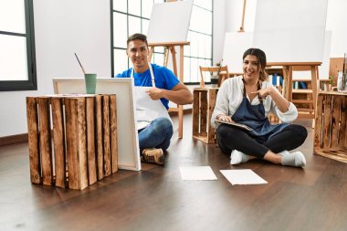 Sanat stüdyosundaki genç İspanyol çift gülümseyen mutlu ve gururlu birini işaret ediyor. 
