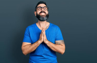 Sakallı, sıradan tişörtlü, gözlüklü, dilenci ve dua eden İspanyol bir adam. Yüzünde umut ifadesi olan çok duygusal ve endişeli bir ifade var. Yalvarıyor. 