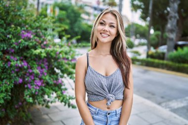 Genç beyaz kız gülümseyerek şehirde mutlu mesut duruyor..