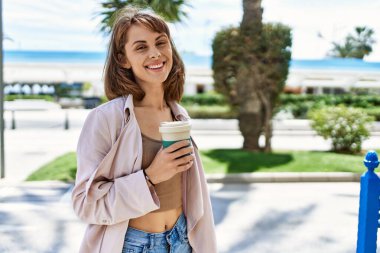 Beyaz kız gülümsüyor, şehirde kahve içiyor..