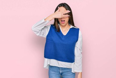 Gündelik kıyafetler giyen genç İspanyol kız şok içinde yüzünü ve gözlerini kapayarak utanmış ifadesiyle parmaklarından bakıyor.. 