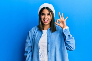 Şirin yün şapkalı, gülümseyen genç Latin kadın el ve parmaklarıyla 