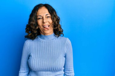 Orta yaşlı İspanyol kadın, sıradan kıyafetler giyiyor. Dilini komik bir ifadeyle dışarı çıkarıyor. duygu kavramı. 