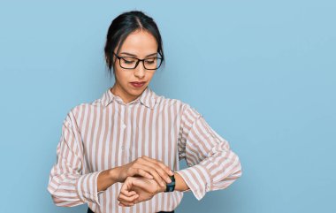 Gündelik kıyafetler ve gözlük takan genç İspanyol kız saati kontrol ediyor, rahat ve kendinden emin. 