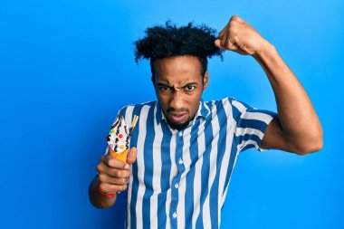 Sakallı, dondurma yiyen Afrikalı genç bir adam öfkeyle bağırıyor, öfkeyle bağırıyor ve el kaldırıyor. 