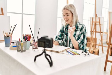 Genç ressam kız mutlu resim çiziyor. Sanat atölyesindeki masa başı resim dersinde otururken..