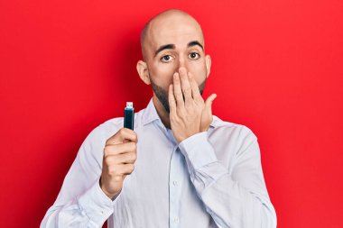 Çıkarılabilir anıları olan genç kel bir adam eliyle ağzını kapatıyor, şok geçiriyor ve hata yapmaktan korkuyor. şaşırmış ifade 