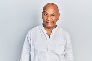 Orta yaşlı, sıradan kıyafetler giyen, kameraya seksi bir ifadeyle bakan, neşeli ve mutlu yüzlü bir Latin.. 